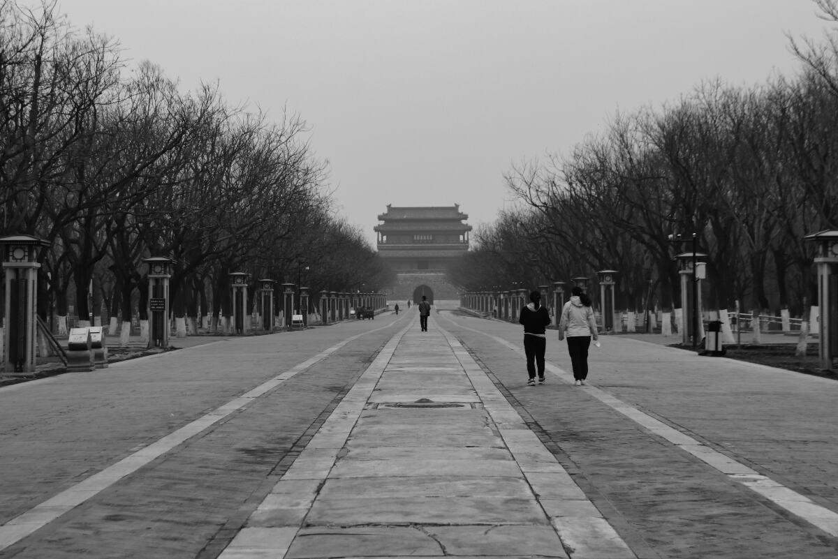 Zuwegung zum Yongdingmen (Tor) in Peking, schwarz-weiß und trostlos: breiter, weitgehend leerer Weg, wenige Menschen, kahle Bäume