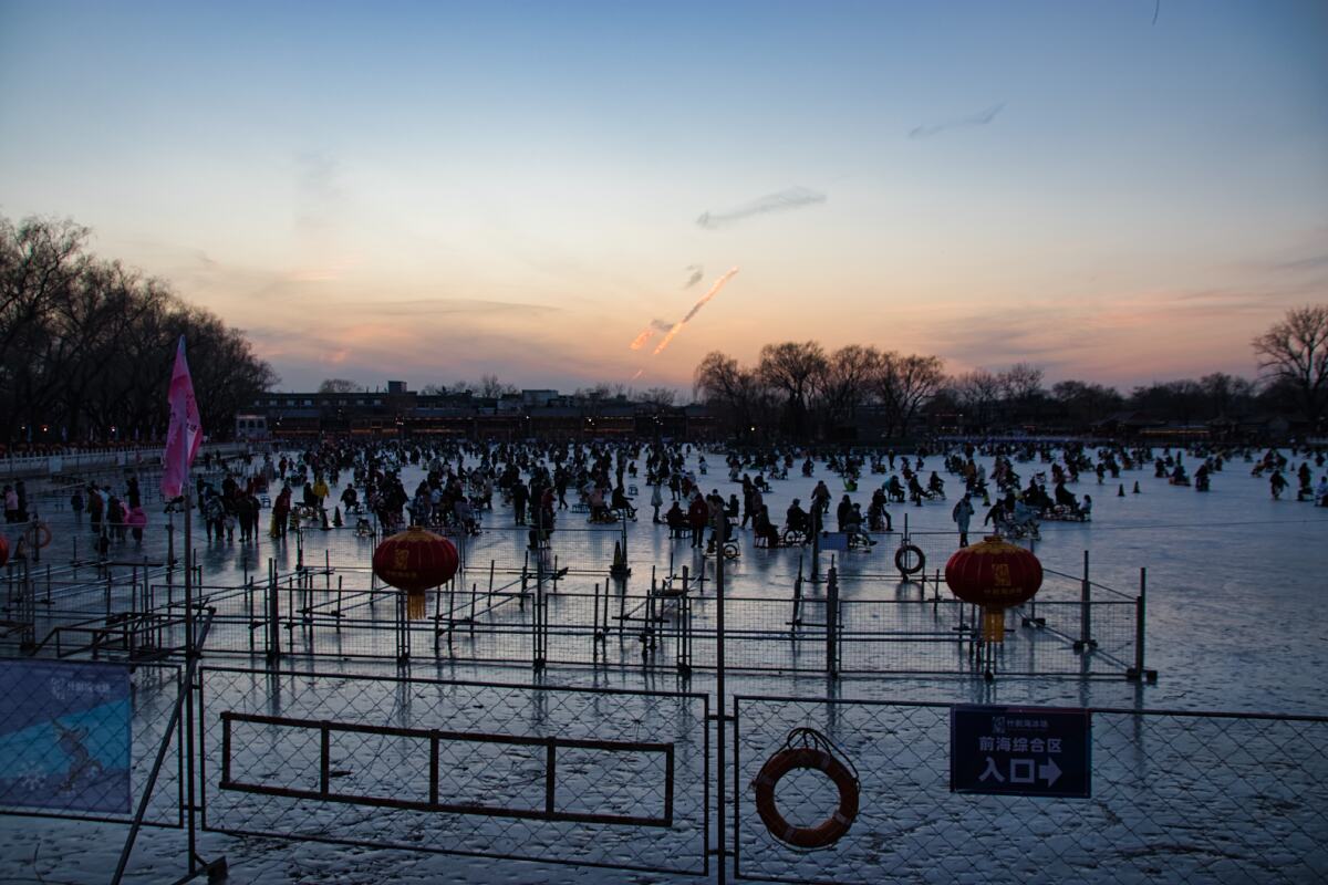 Qianhai in der Dämmerung, auf der Eisfläche tummeln sich viele Menschen