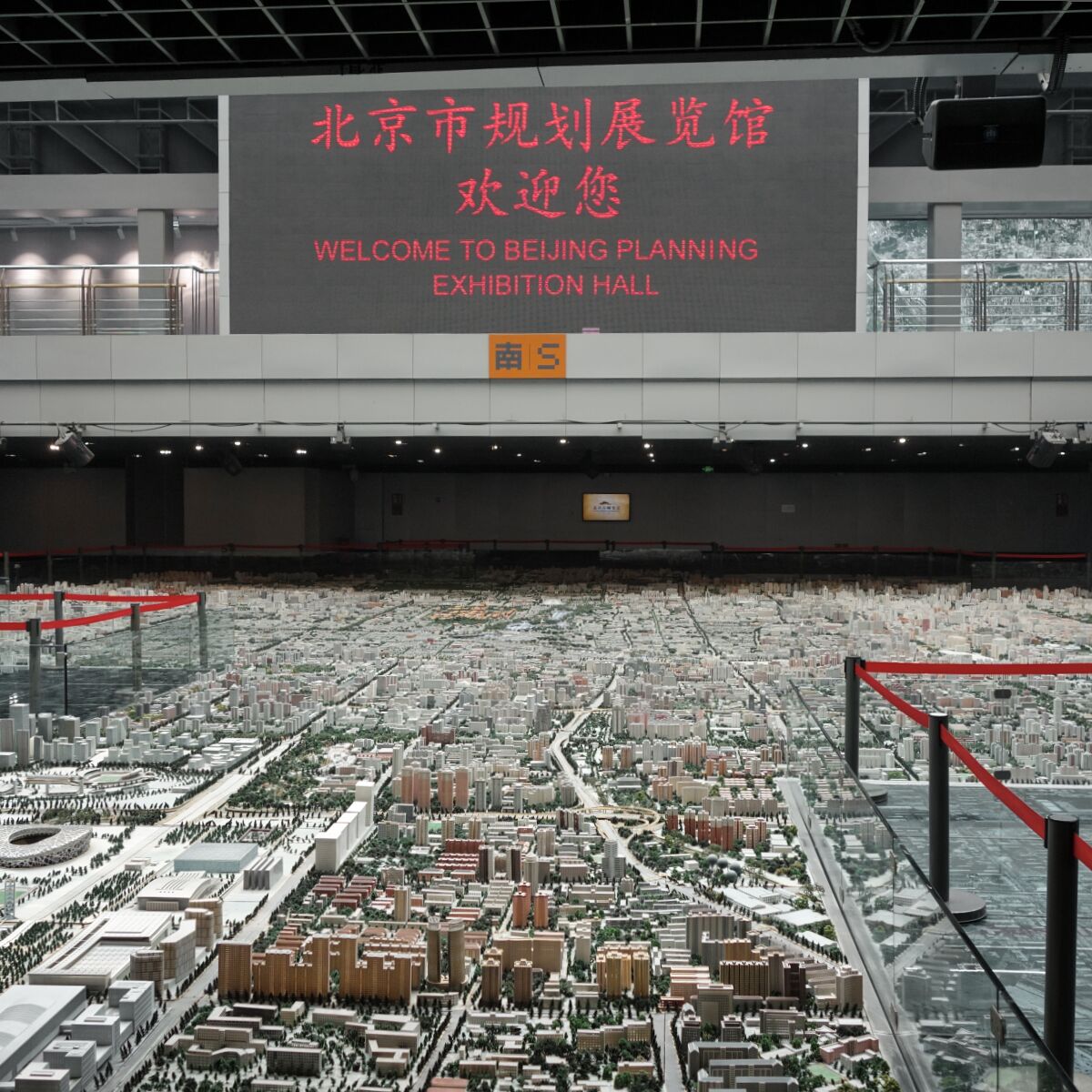 Überblick über die Halle mit dem Pekinger Stadtmodell, an einer Empore ein LED-Bildschirm mit dem Text "Welcome to Beijing Planning Exhibition Hall" auf Englisch und Chinesisch